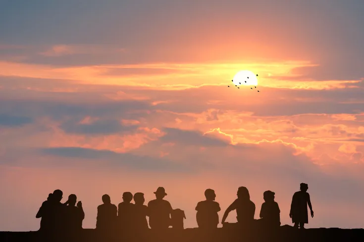 Pessoas diversas unidas ao pôr do sol, em um momento de conexão, plenitude e entrega, simbolizando amor, pertencimento e liberdade.